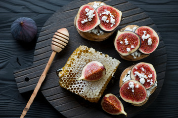 Fototapeta na wymiar Bruschetta with figs and honey on a dark wooden serving board