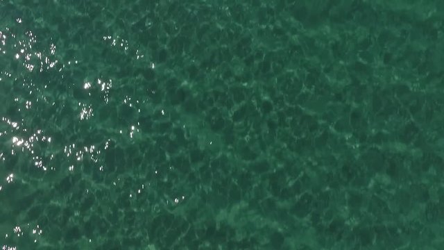 Close shot lake, see or ocean water surface. Higher speed with twinkling sun. wavy surface transparent water and sun reflecting during summer day. emerald color water surface