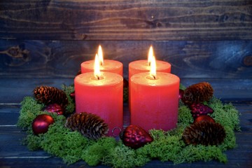 vier rote Adventskerzen mit Moos