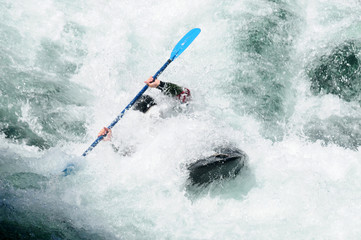 Active kayaker rolling and surfing in rough water
