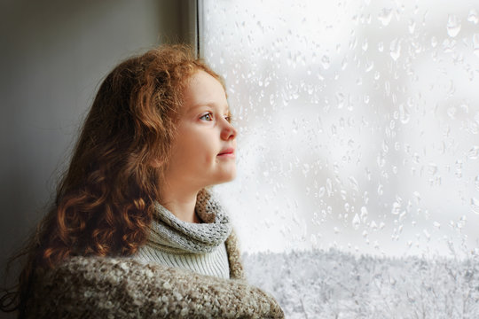 Happy Child Looking Out The Window With Wet Glass Bad Weather.