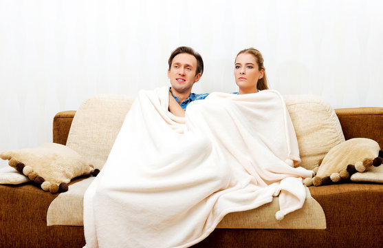 Smiling Loving Couple Sitting On Couch With Blanket