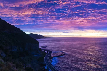 Gardinen Sea Cliff Bridge bei Sonnenaufgang mit schönem rosa und lila, violettem Himmel und Ozeanufer im Hintergrund. Die Brücke ist Teil des Grand Pacific Highway und ist eine malerische Route entlang der Küste von NSW, Australien © Olga K