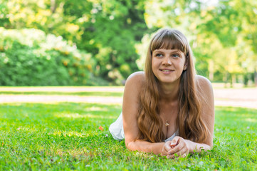 Young beautiful woman in white dress lying on the grass