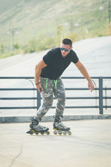 young man with inline skates ride in summer park seafront outdoor rollerskater