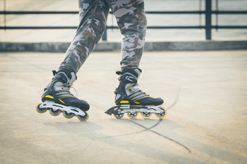 Rollerskater inline in action. Male legs shod in roller skates ride along the promenade