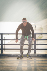 young man with inline skates ride in summer park seafront outdoor rollerskater