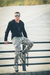 young fit man with inline skates rest in summer park after workout outdoor rollerskater