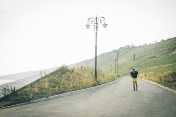young man with inline skates ride in summer park outdoor rollerskater