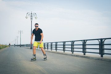 young man with inline skates ride in summer park seafront outdoor rollerskater