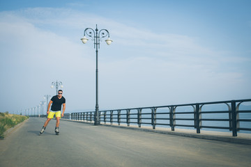 young man with inline skates ride in summer park seafront outdoor rollerskater