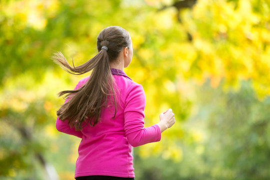 Profile portrait of a young attractive smiling woman jogging away in the autumn. Concept photo, rear view
