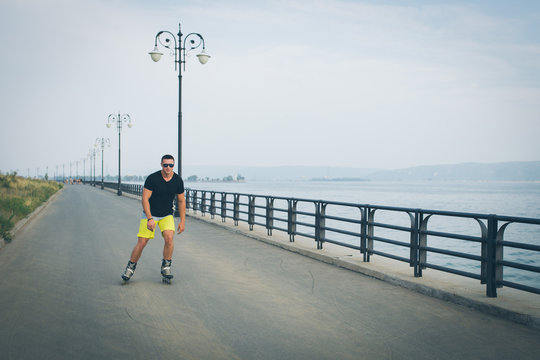 young man with inline skates ride in summer park seafront outdoor rollerskater