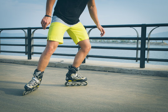 Rollerskater inline in action. Male legs shod in roller skates ride along the promenade