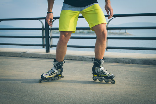 Rollerskater inline in action. Male legs shod in roller skates ride along the promenade