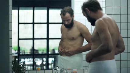 Unhappy, sad man checking his belly in front of mirror in bathroom
- Powered by Adobe