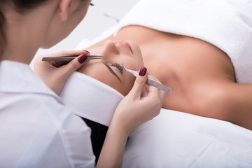 Professional beautician undergoing eyelash extension procedure
