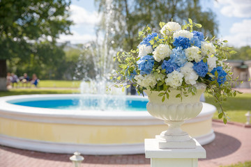 A blurred picture of a fountain and a bouquet in Greek vase in t