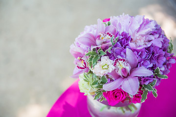 A bouquet made of violet flowers stands on the pink tablecloth