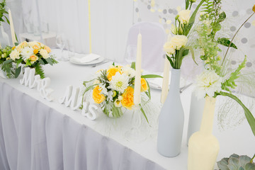 Newlyweds table decorated with flower bouquets in white and yell