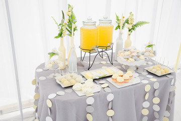 Table with sweets decorated in gray, white and yellow tones stan