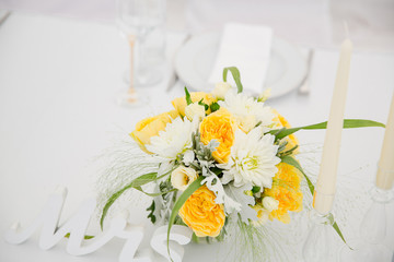 A stunning bouquet made of white and yellow flowers stands betwe