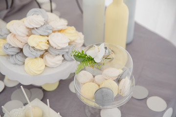 Sweets table decoration. Gray and yellow macaroons under a glass