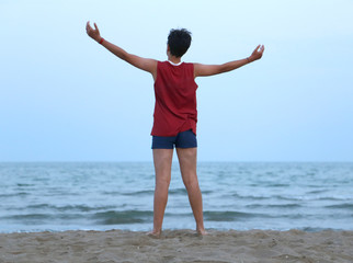 guy with raised arms on the seashore at dusk