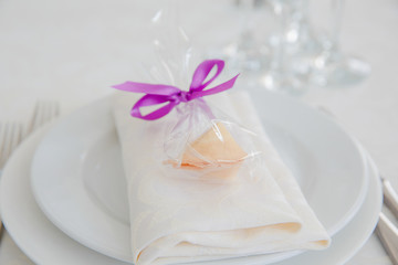 Sweets in a packet with violet ribbon stand on the crockery serv