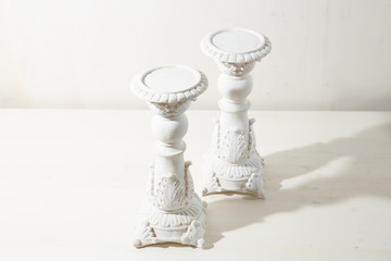 Thick white candleholders with classic design on the white backg