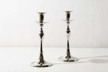 Two steel candleholders stand on the white background