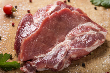 Raw pork steaks on wooden board