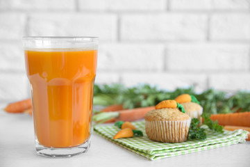 Fresh carrot juice with cupcakes on light background