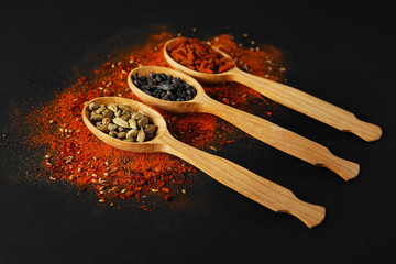 Spices in wooden spoons on a dark background
