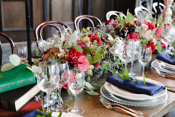 Books and flowers stand on the wooden dinner table