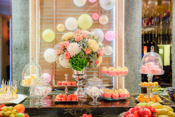 Bright colored table with sweets and flowers
