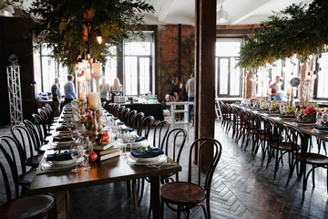 Dinner tables stand in a beautiful loft decorated with green gar