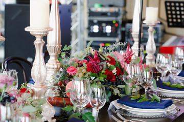 Rich decor of dinner table full of flowers and high candleholder