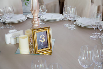 Table number design. Godlen wooden frame surrounded with candles