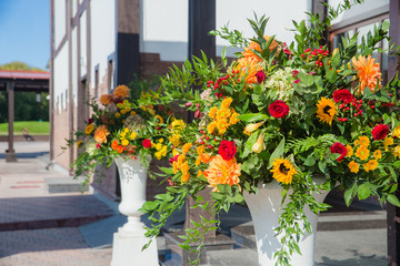 Rich autumn bouquets in white Greek vases stand behind an entran