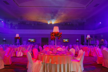 Round dinner tables covered with pink light