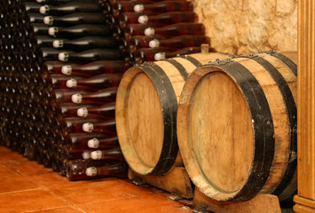 Wooden barrels and bottles with wine  in cellar