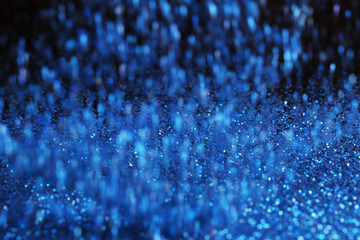 Glittering blue sparkles falling on dark background
