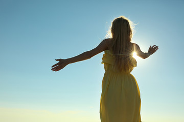 Fototapeta na wymiar Silhouette of young woman on blue sunny sky background