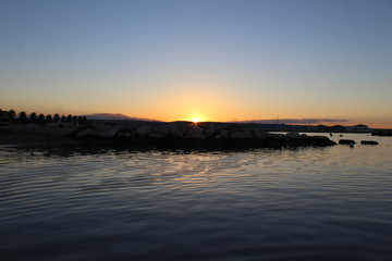 Silhouette People In Calm Sea At Sunset