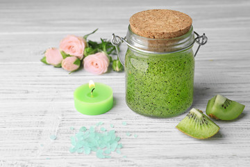 Body scrub and kiwi on wooden table