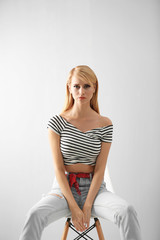 Naklejka premium Pretty young woman in casual clothes sitting on chair against light background