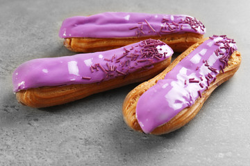 Delicious glazed eclairs on light textured background