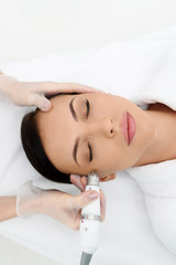 Beautician using ultrasound equipment for face treatment