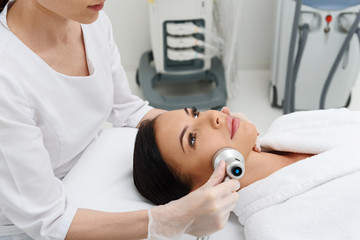 Obraz premium Calm young woman receiving cavitation skincare treatment